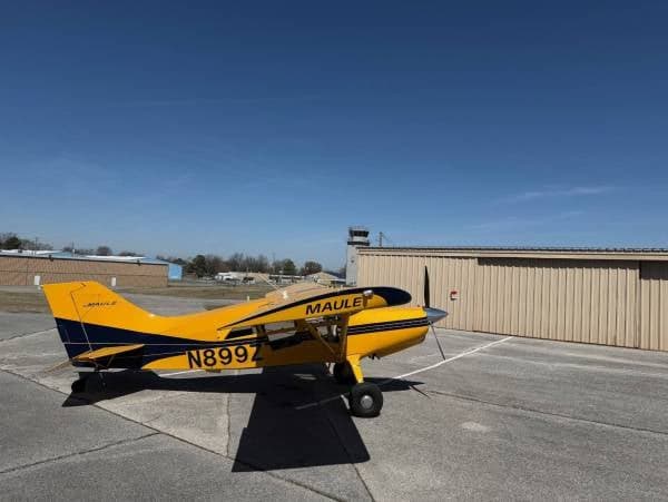 A yellow and blue Maule M-7-235 aircraft with registration N899Z parked on the tarmac.
