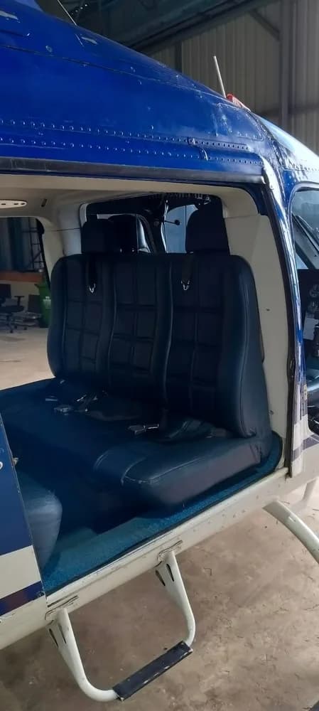 View of the blue leather passenger seats inside the helicopter cabin, with a partial view of the cockpit.
