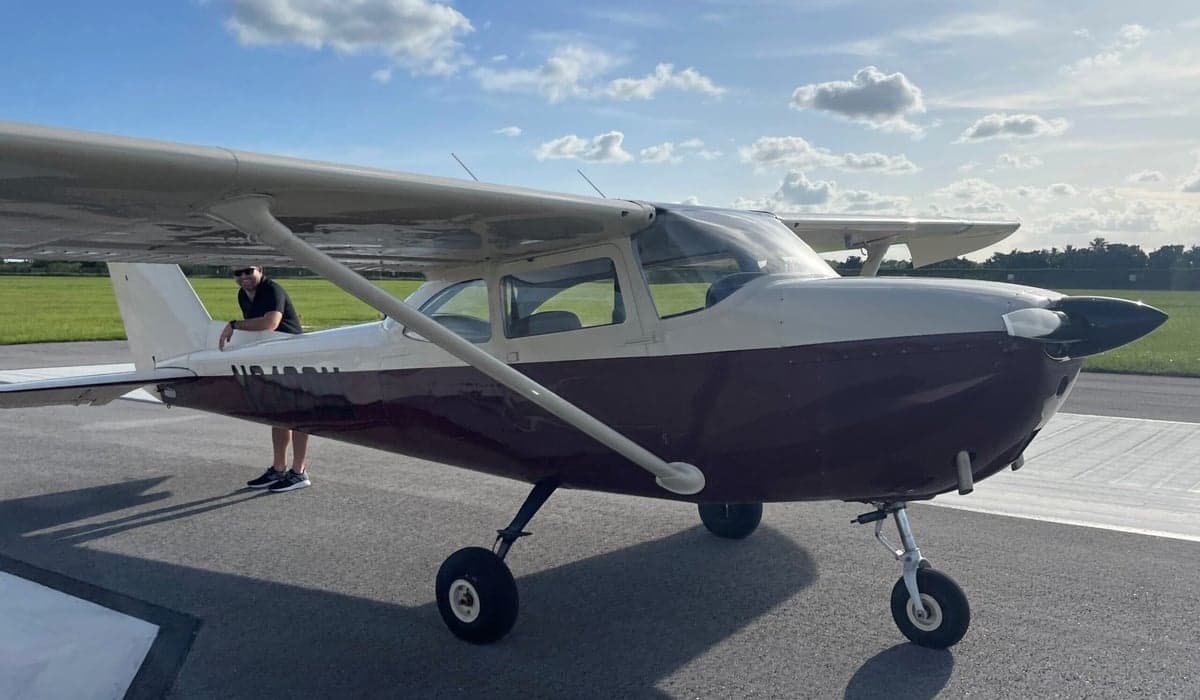 A Cessna 150 aircraft with a brown and white paint scheme is parked on the tarmac.