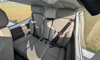 The interior of the aircraft shows the front seats with seatbelts.