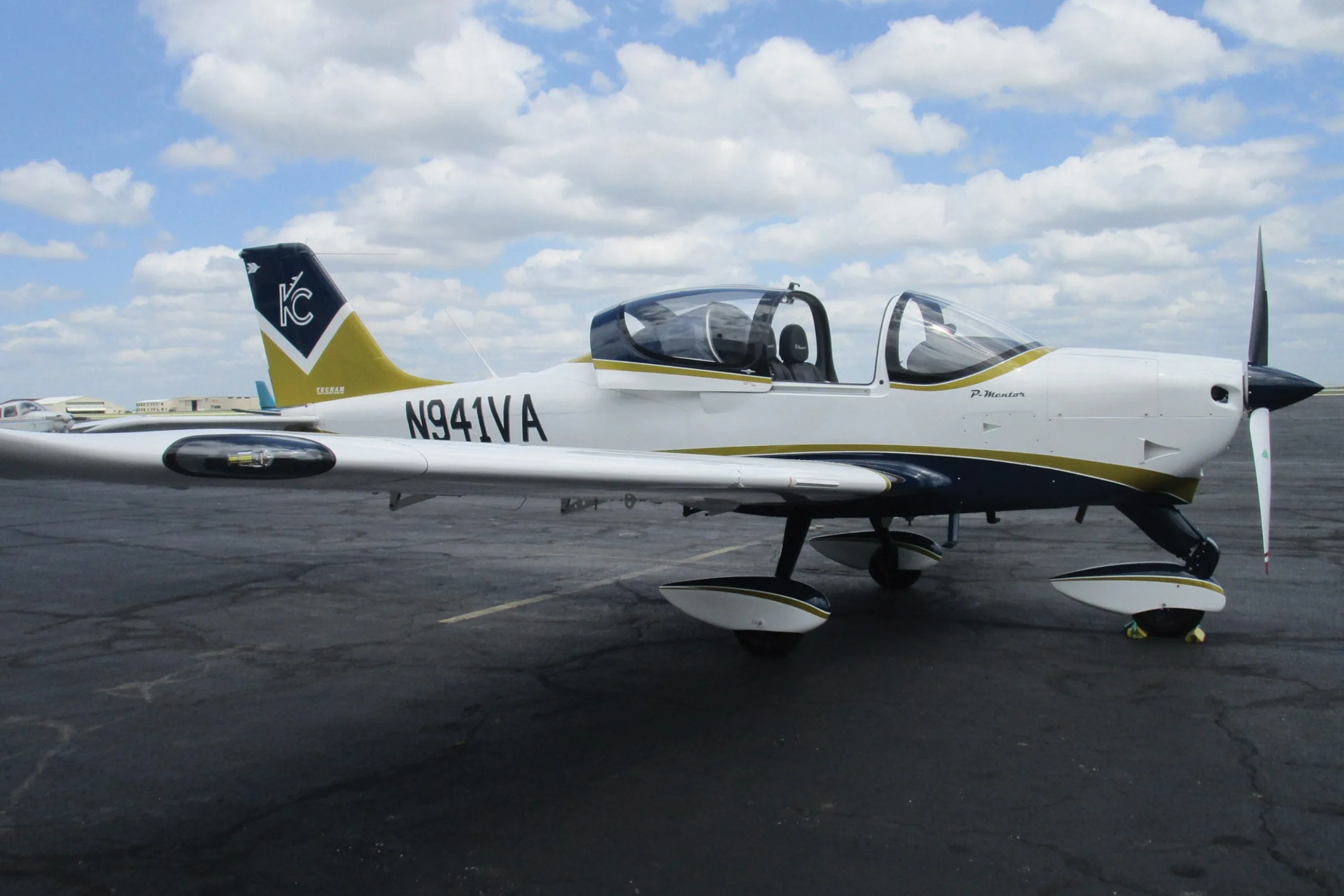 A white and gold light aircraft parked on the tarmac.