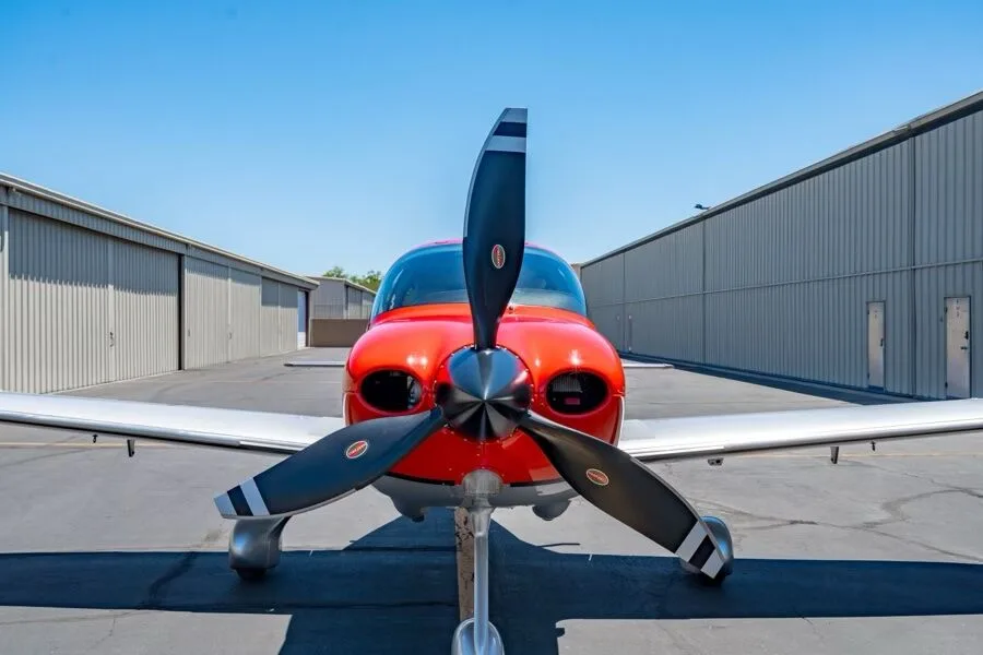 Close-up front view of the propeller and nose of a red and silver Cirrus SR22T aircraft (N566TT).