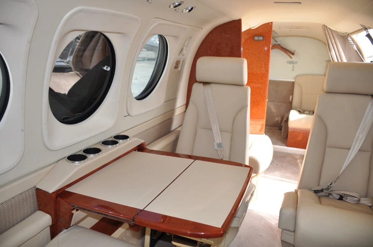 Interior view of the aircraft cabin with a table and cream-colored leather seats.