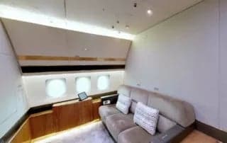 A view of the aircraft's interior, featuring a couch and a wooden table.