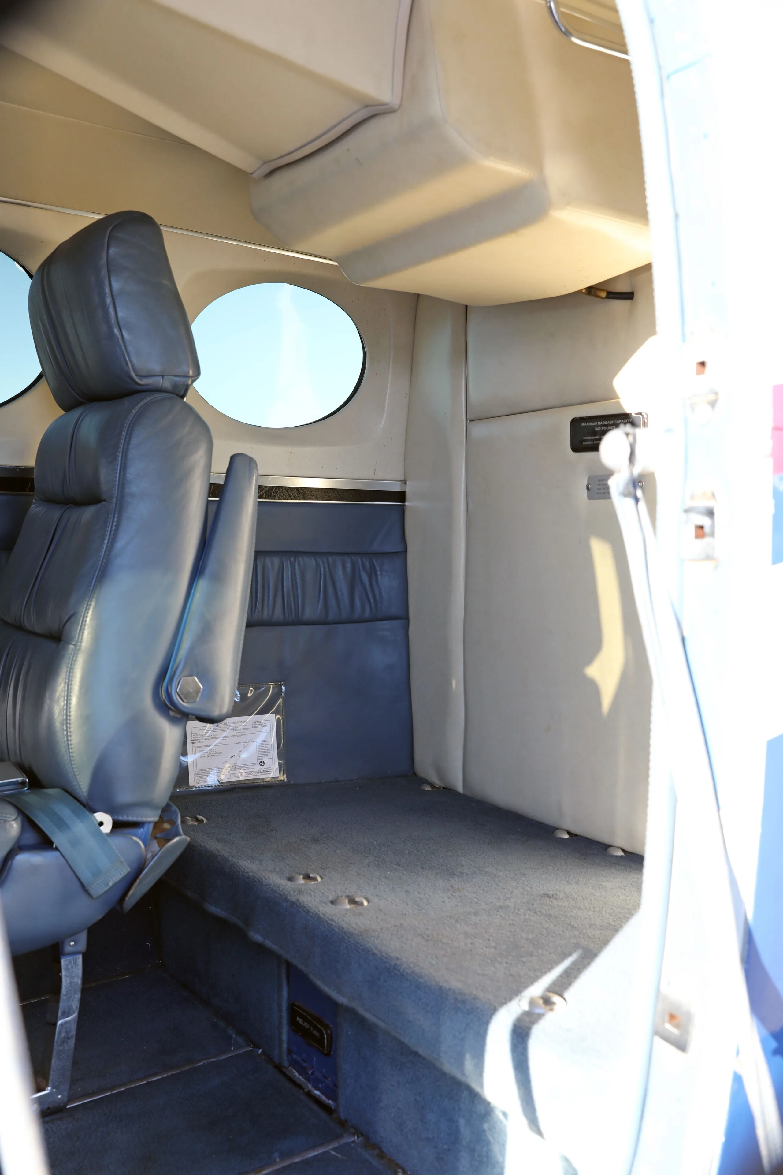 The rear cabin interior of the Cessna 340, featuring a dark blue carpeted floor and light-colored walls.