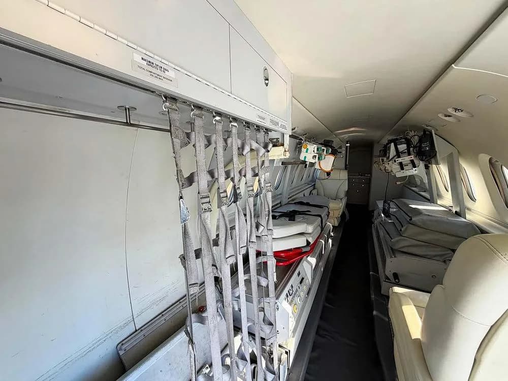 An interior view of an air ambulance cabin, showing medical equipment and a stretcher on the left.
