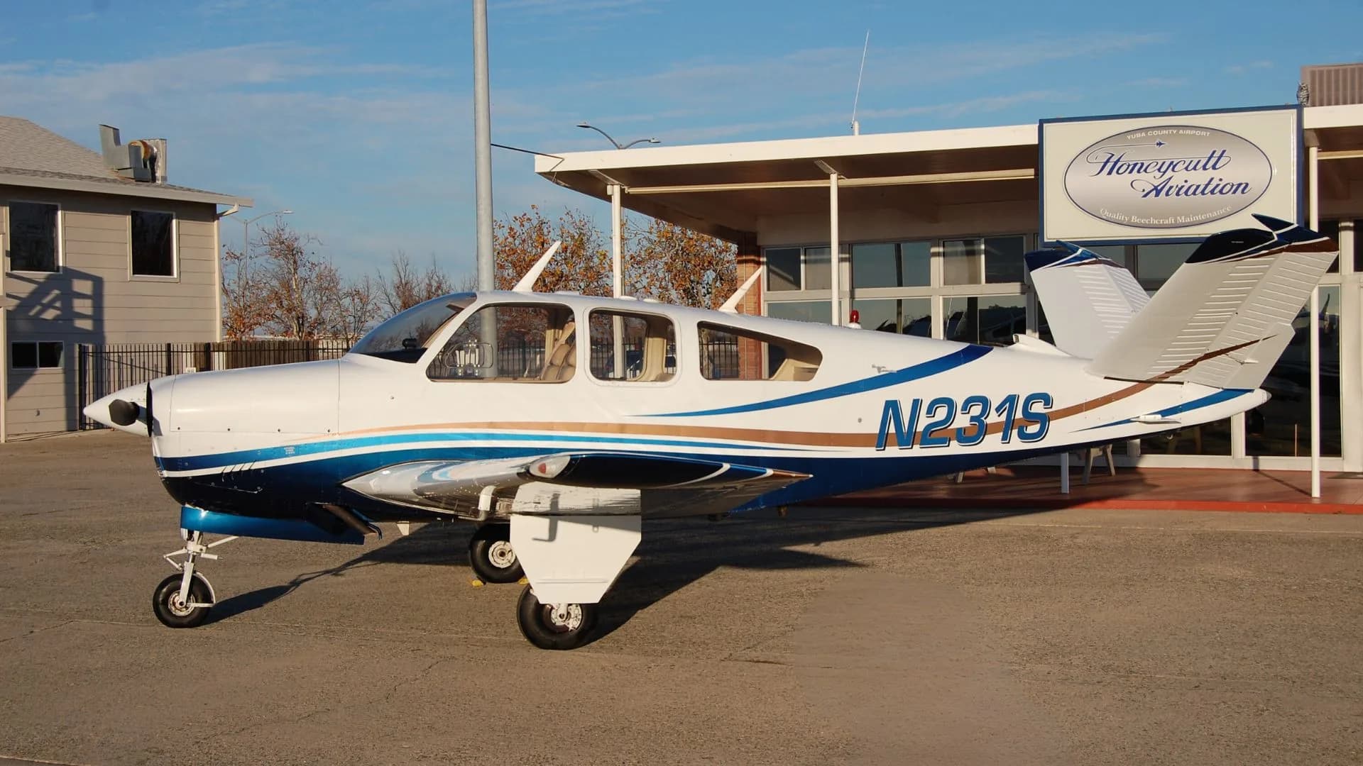 Side view of the N231S aircraft parked on the tarmac in front of a building.