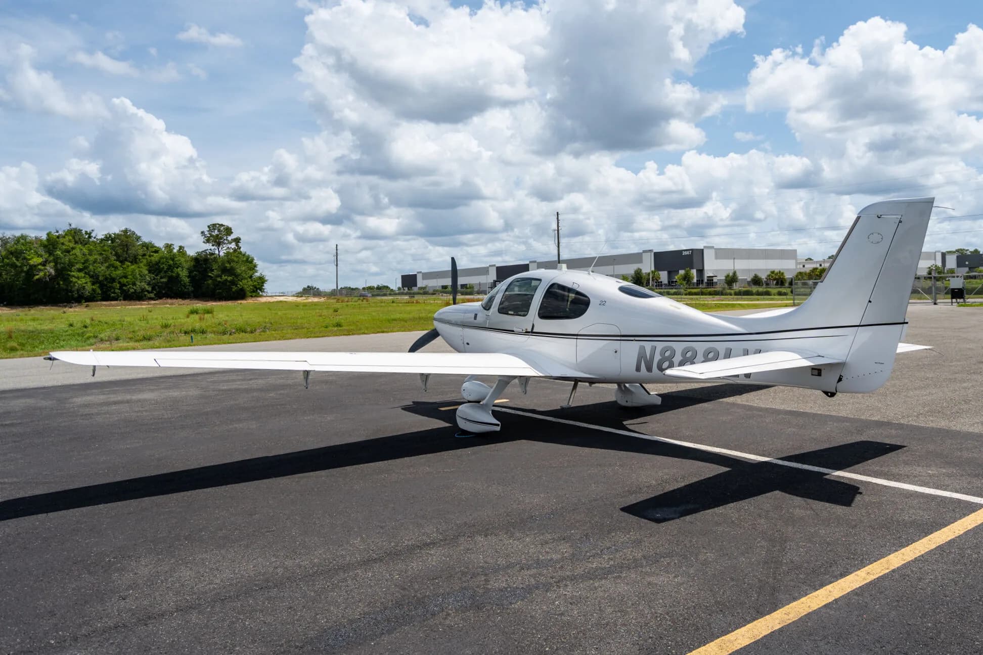 Three-quarter rear view of a silver Cirrus SR22 aircraft (N888LV) parked on an airfield.