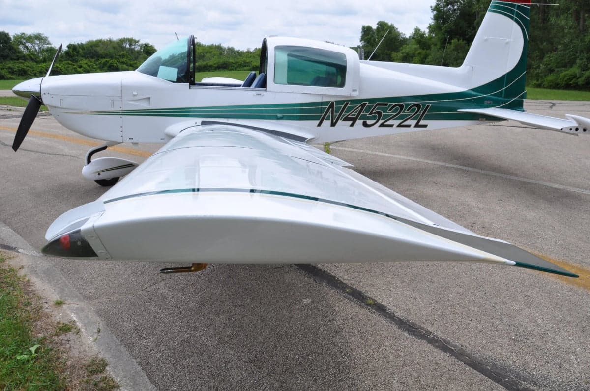 Close up of the wing and fuselage of a white and green aircraft.