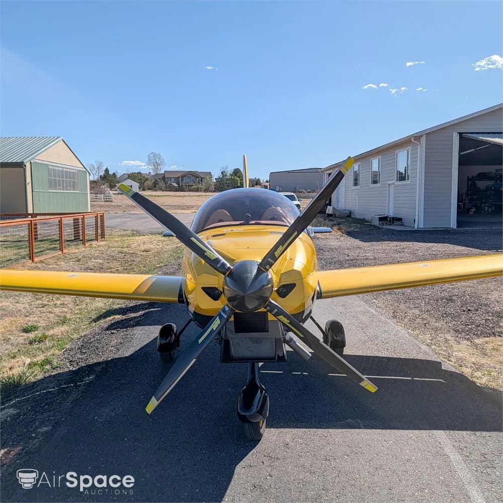 A head-on view of a yellow and black Freccia F200 aircraft with a three-bladed propeller, parked on an asphalt ramp.