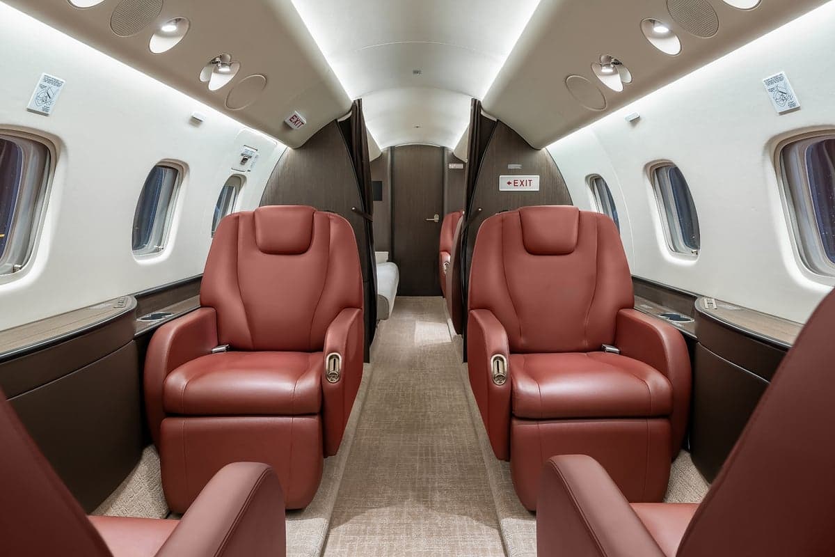 View of the aircraft interior with red leather seats and a neutral color scheme.