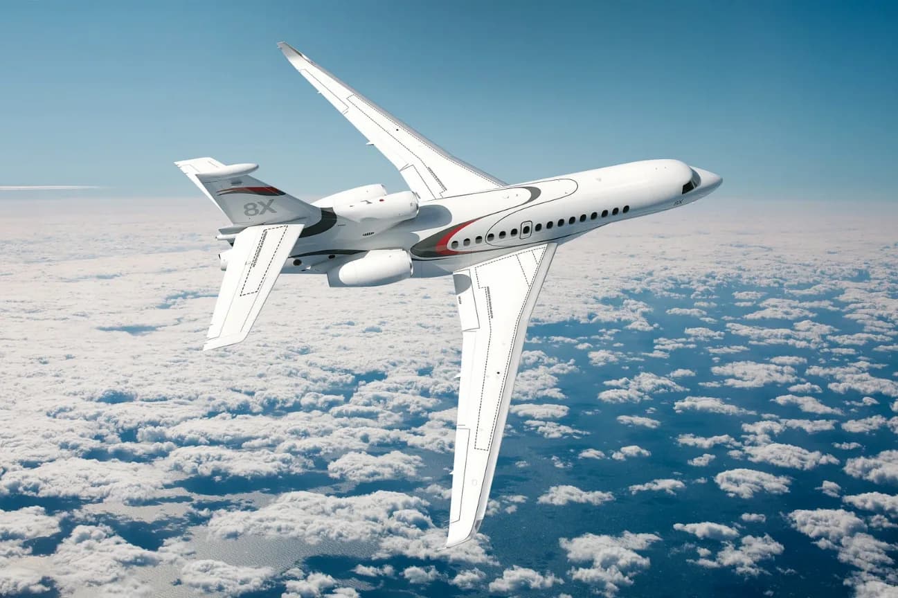 A white jet with red accents flying above the clouds.