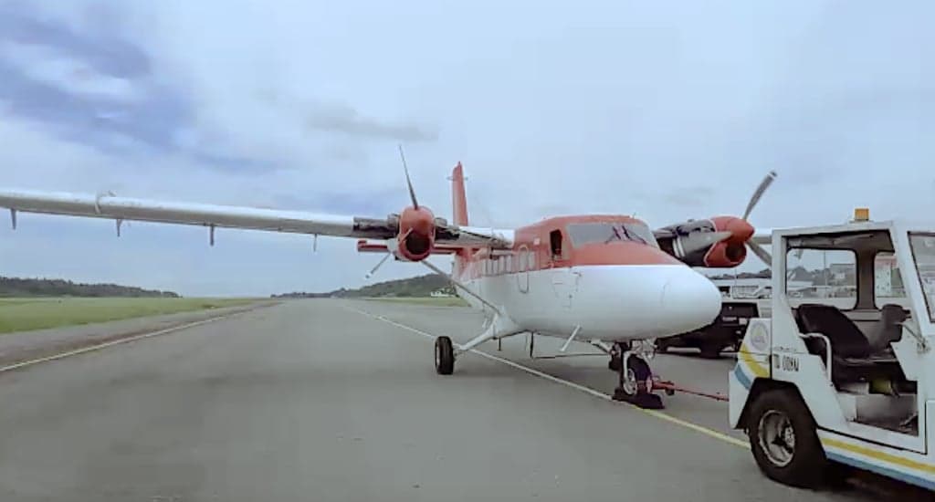 A red and white twin engine aircraft on a runway.