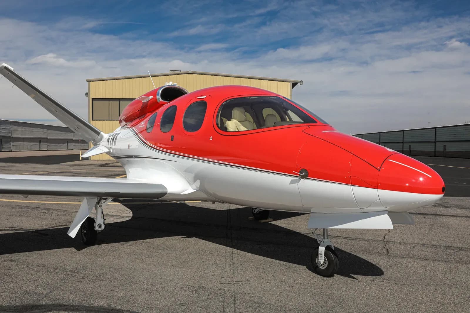 A red and white Cirrus Vision Jet (N1WK) parked on a tarmac, viewed from the front-right.