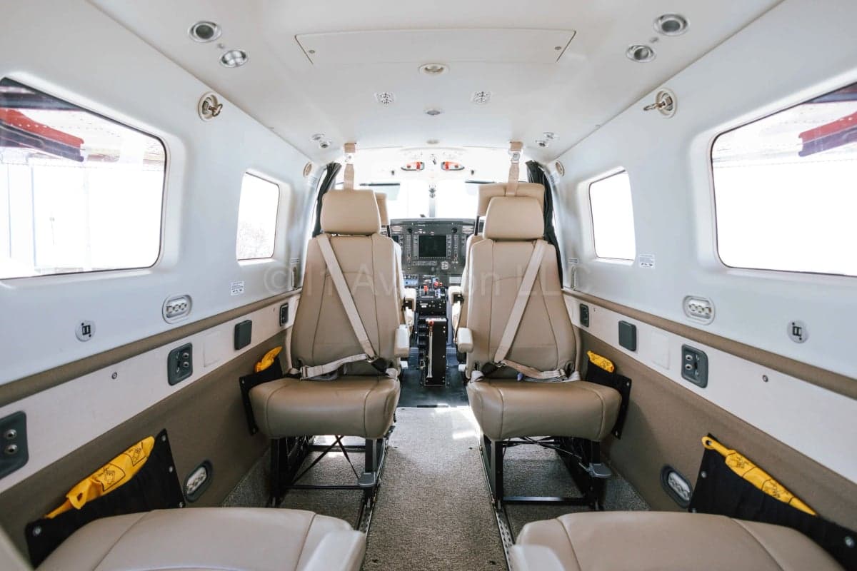 The interior cabin of the aircraft, showing multiple rows of beige leather seats leading towards the cockpit.