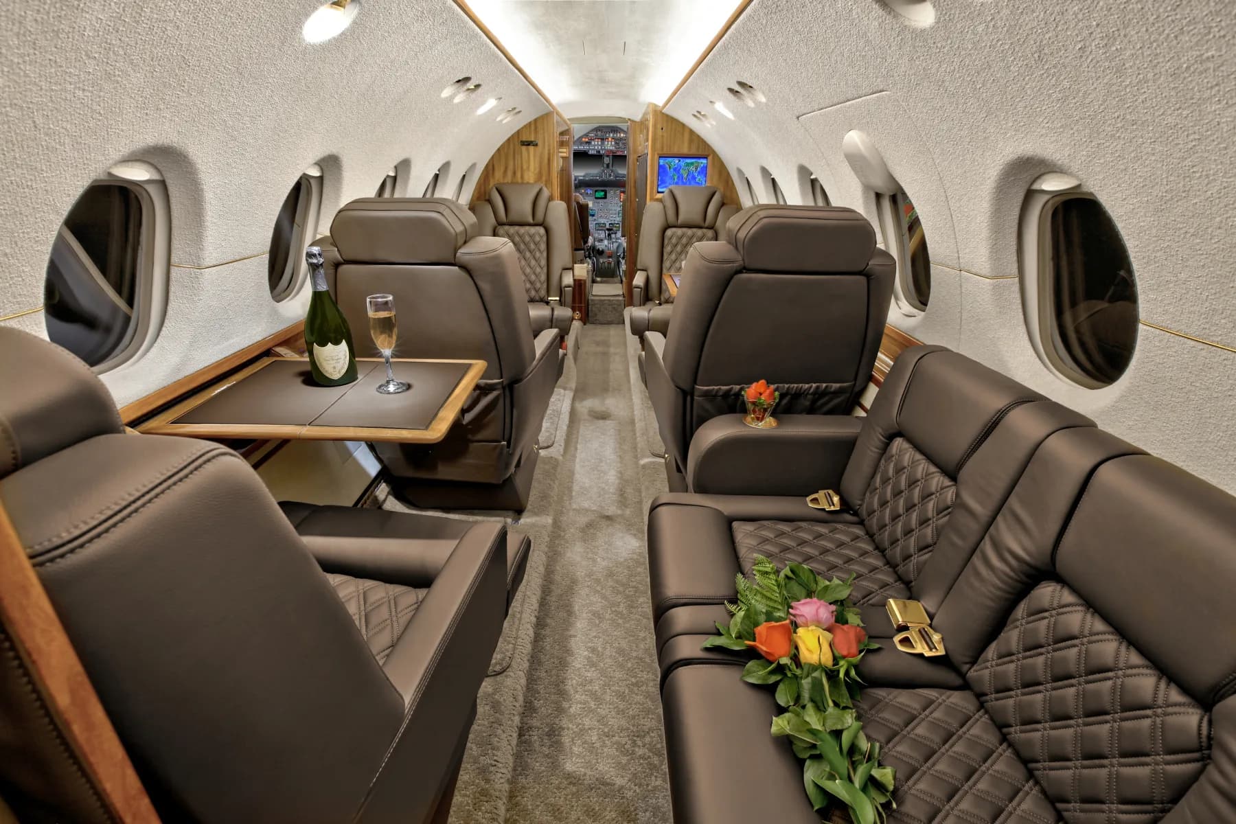 View of the aircraft's interior cabin with leather seats and a table set with champagne.