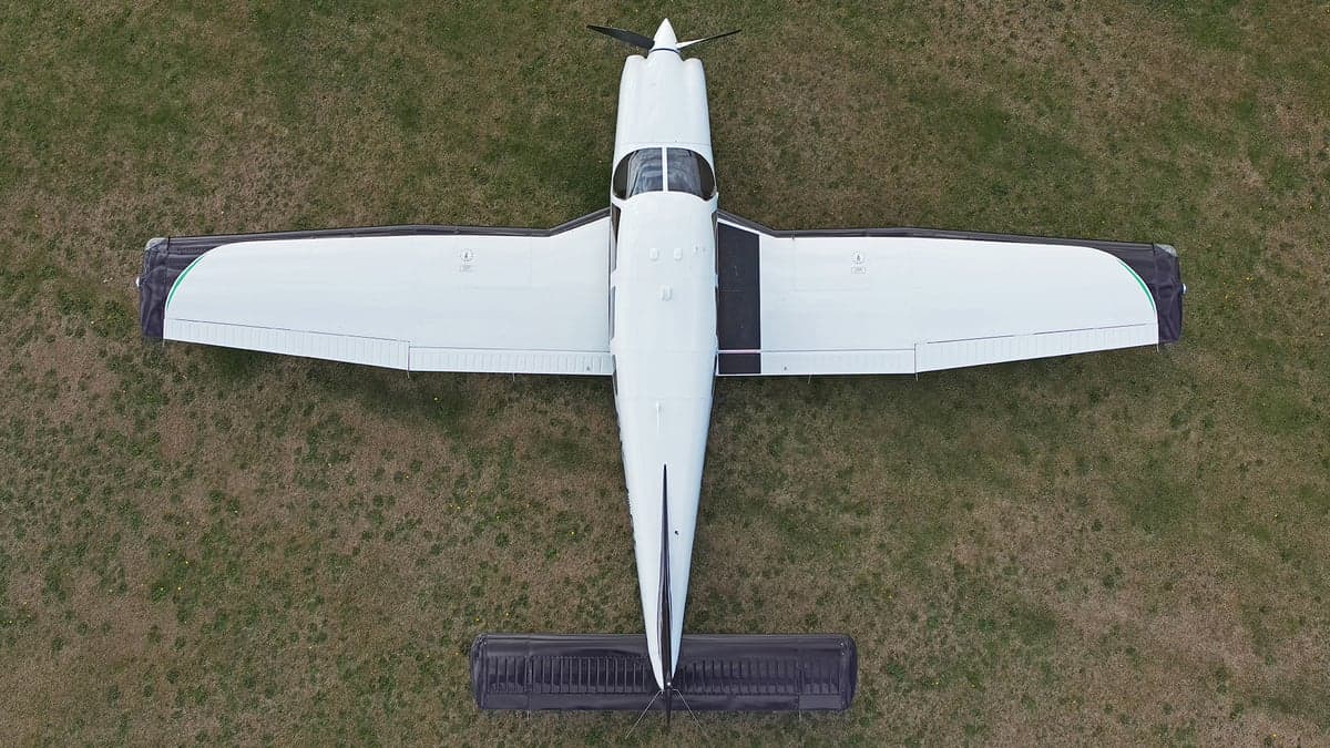 Overhead view of a white and black aircraft on a grassy field.