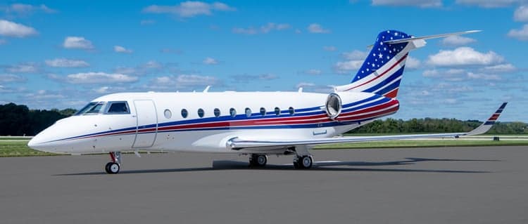 A Gulfstream G550 with a custom American flag paint scheme parked on the tarmac.