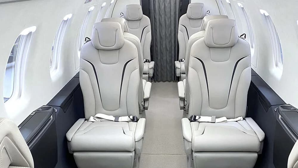 Interior view of the aircraft cabin with cream-colored leather seats and dark wood trim.
