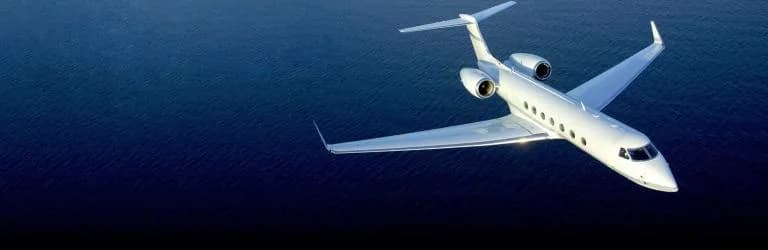 A white jet flies over the ocean.