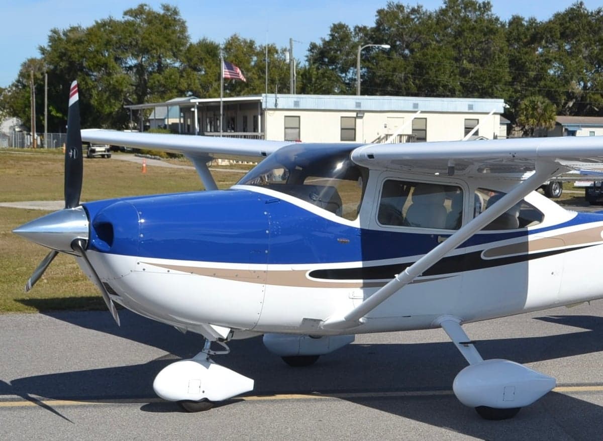 A Cessna 182 Skylane with a blue and white paint scheme parked on the tarmac.