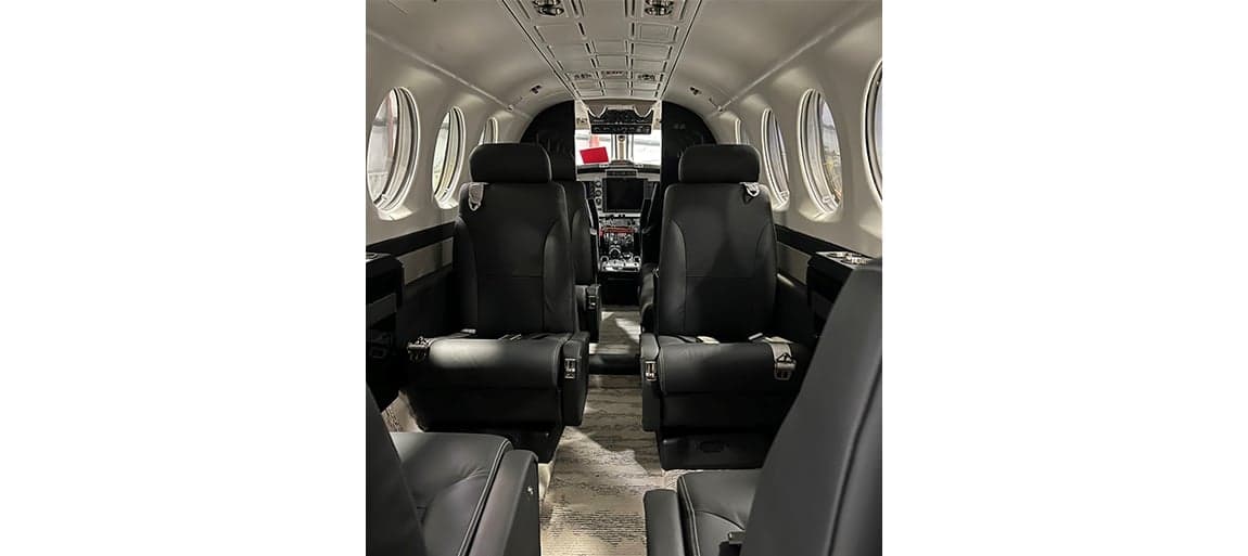 View of the aircraft interior showing the black leather seats and carpeted floor.