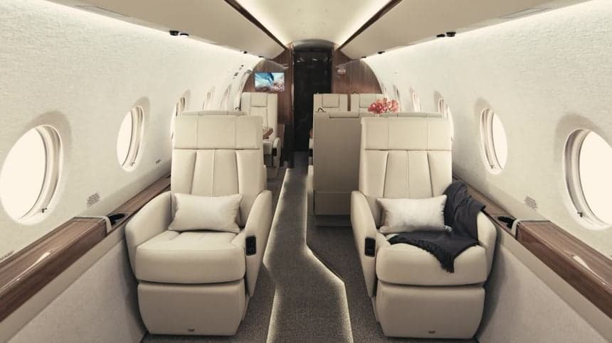 A view of the interior cabin of a private jet with leather seats and wood trim.