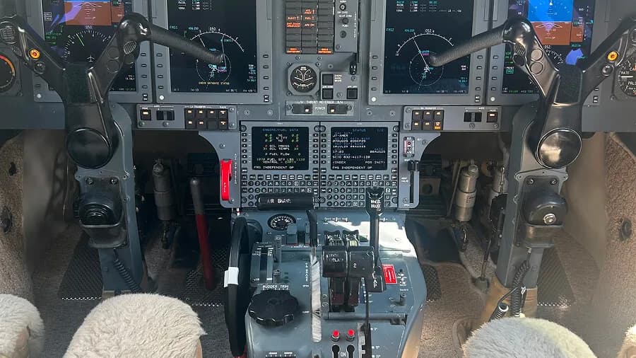 The cockpit of a business jet, showing the instrument panel, flight controls, and center console.