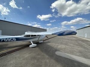 Cessna 172 Skyhawk, registration N759CB, parked on the tarmac in front of a hangar.