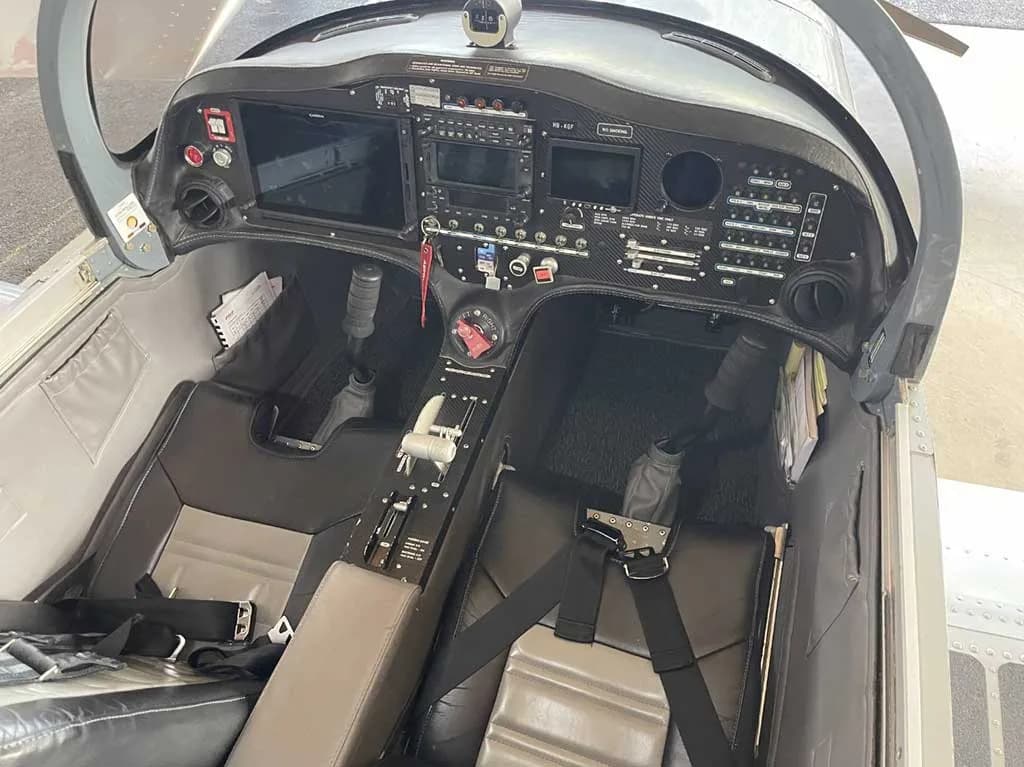 An overhead view of the aircraft cockpit, featuring the instrument panel, dual controls, and two seats.