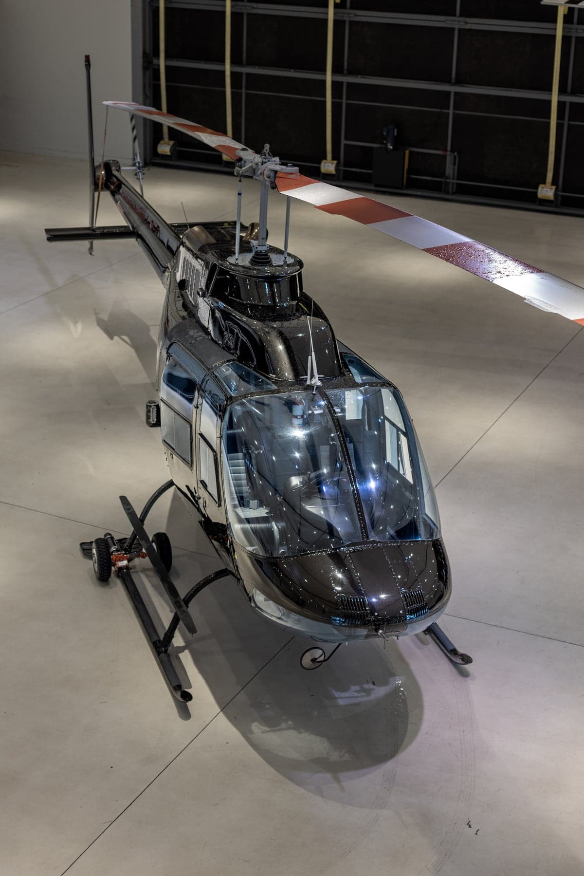 A black helicopter is parked in a hangar.