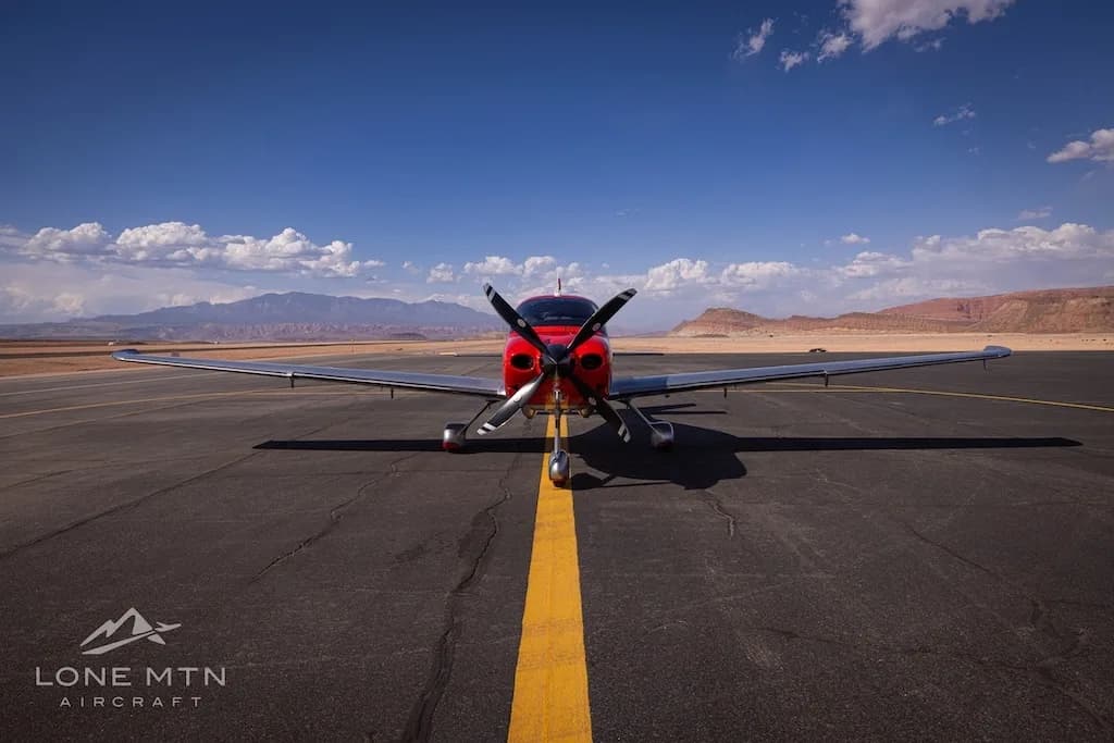 A head-on view of a red and silver Cirrus SR22T aircraft (N605FB) on an airfield with a yellow centerline.