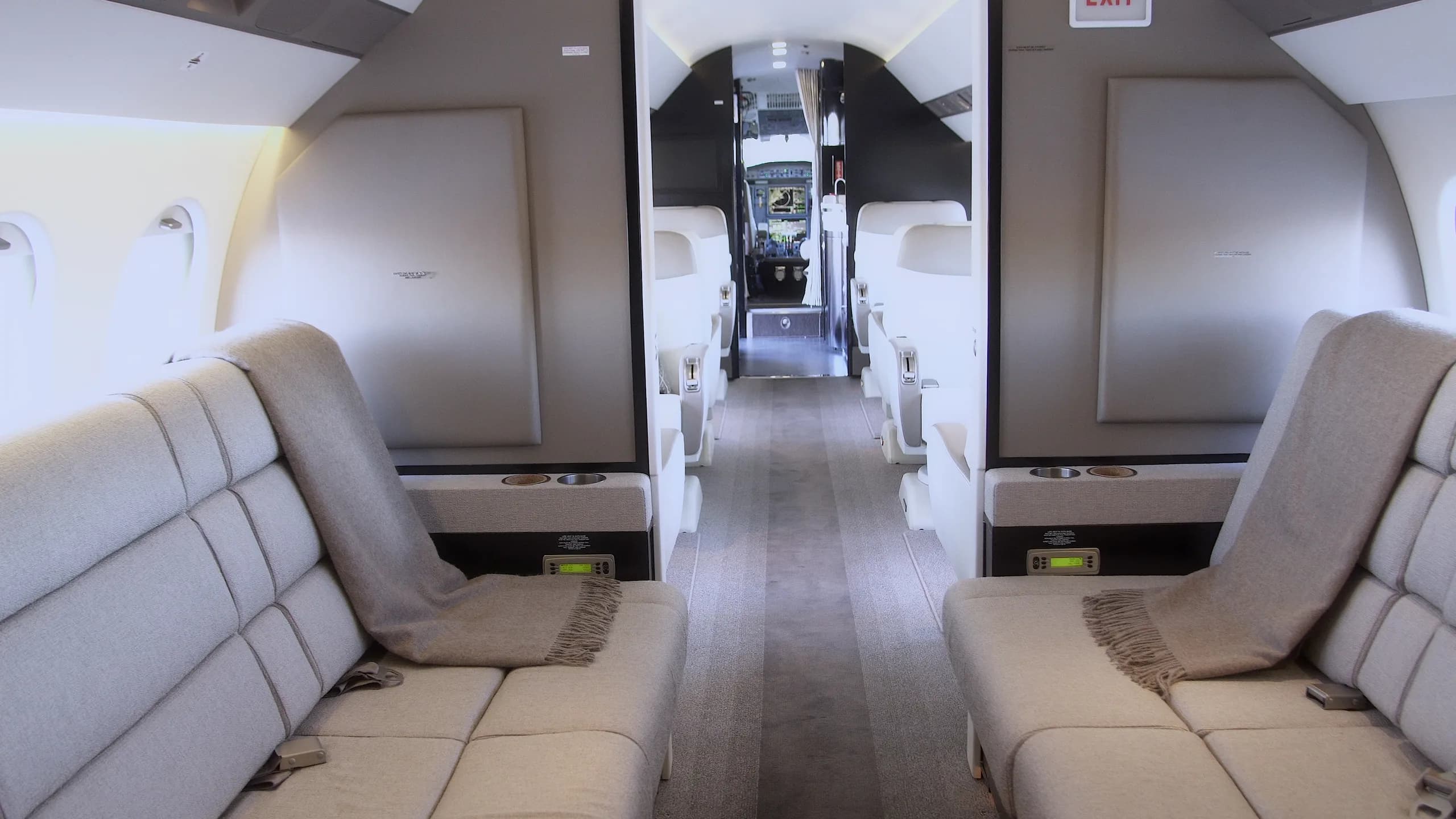 The spacious cabin of a business jet, featuring facing divans and individual seats further down the aisle.