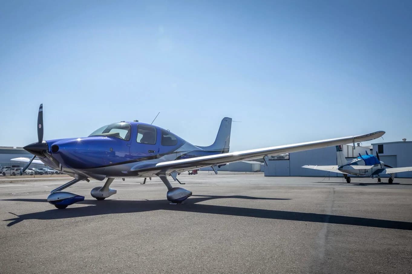 A three-quarter front view of the blue and silver Cirrus SR22 aircraft, N275MG, on an airport tarmac.