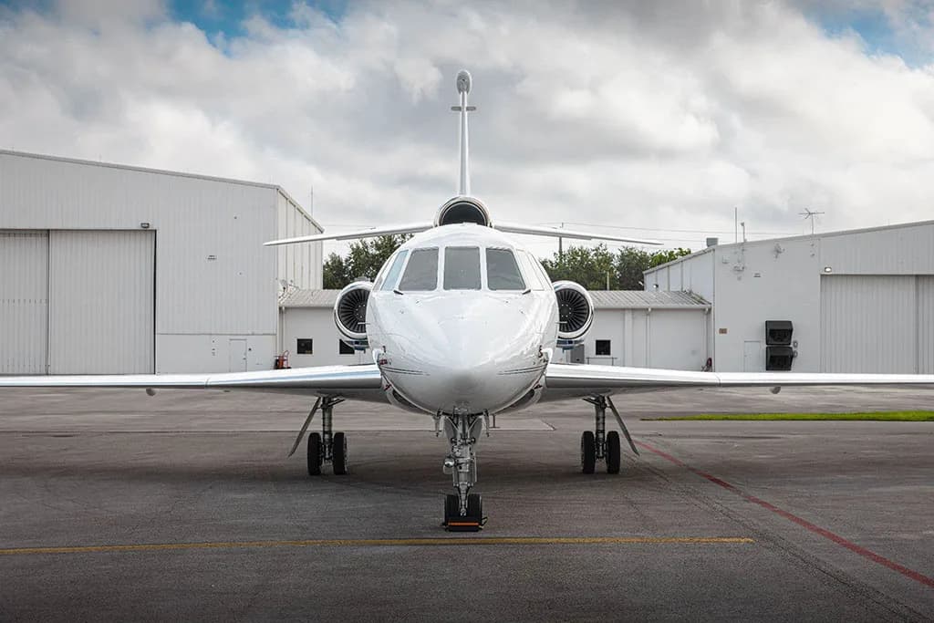 A head-on view of a white business jet with blue stripes, tail number N264RV, parked on an airfield.