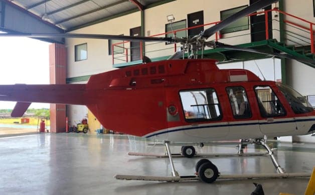 Red and white helicopter inside a hangar.