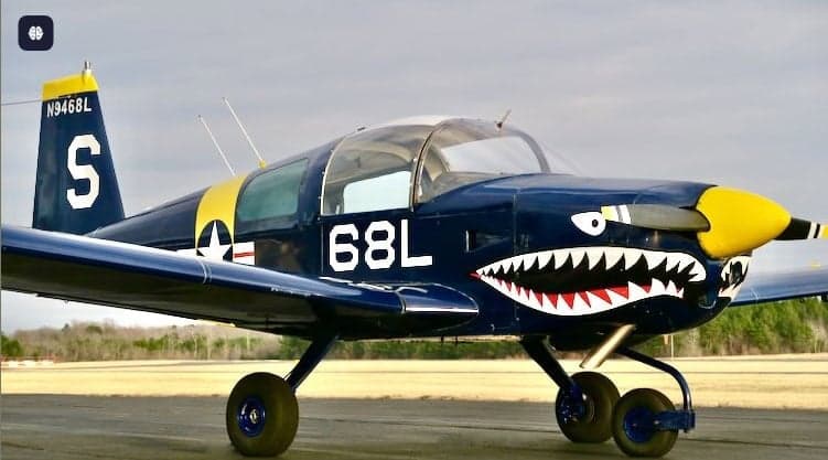 A blue and yellow aircraft with a shark mouth design on the nose.