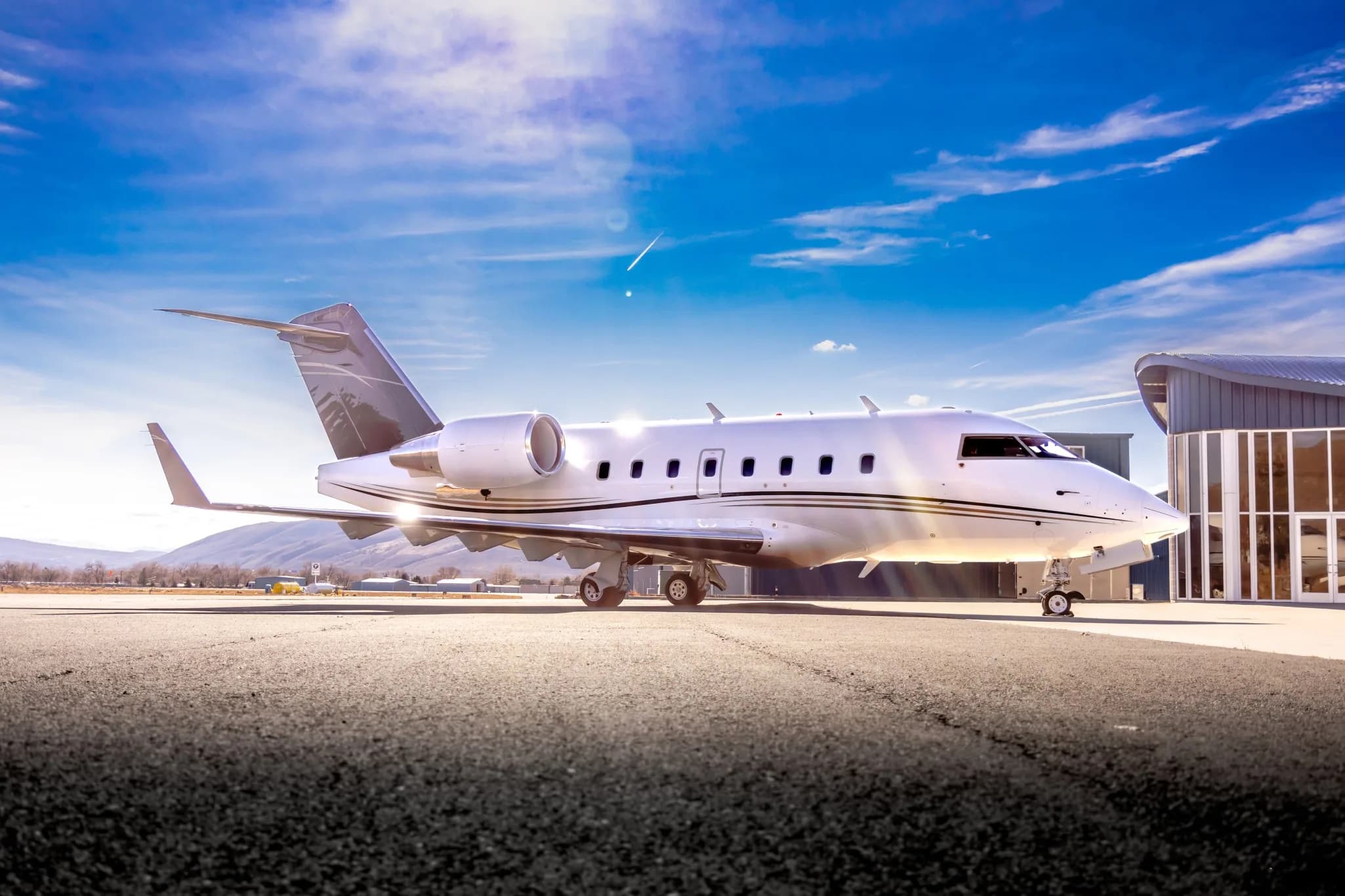 Side view of a white and gray Challenger business jet on the tarmac.