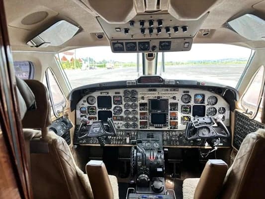 View of the King Air aircraft's cockpit from the cabin, showing the instrument panel and controls.
