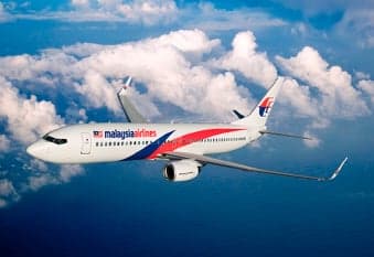 A Malaysia Airlines Boeing 737 in flight against a cloudy sky.