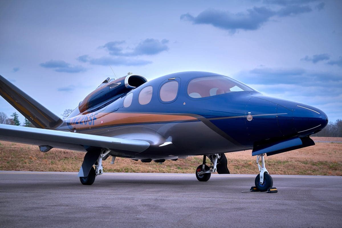 A Cirrus Vision Jet on the tarmac with a blue and silver paint scheme.