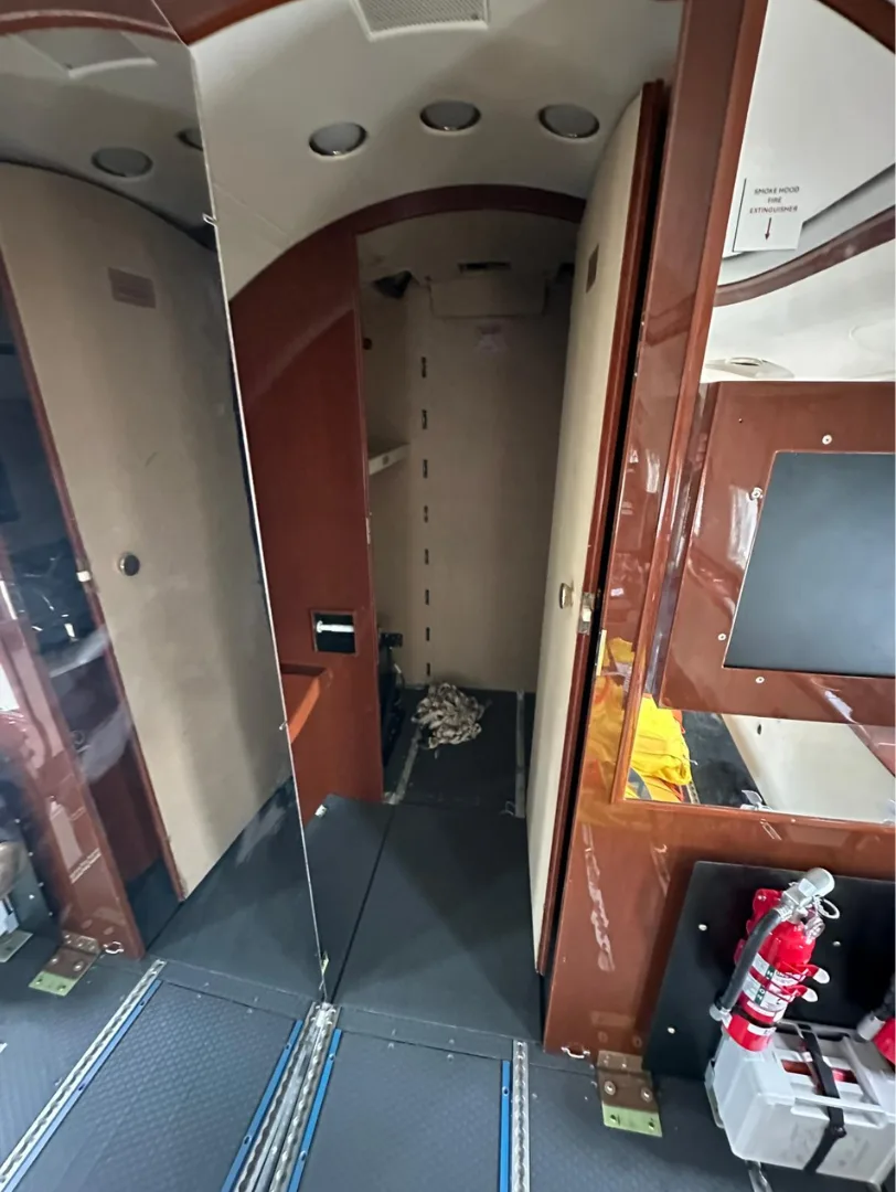 A section of the aircraft's interior with wooden paneling, a mirror, and a fire extinguisher mounted on the wall.