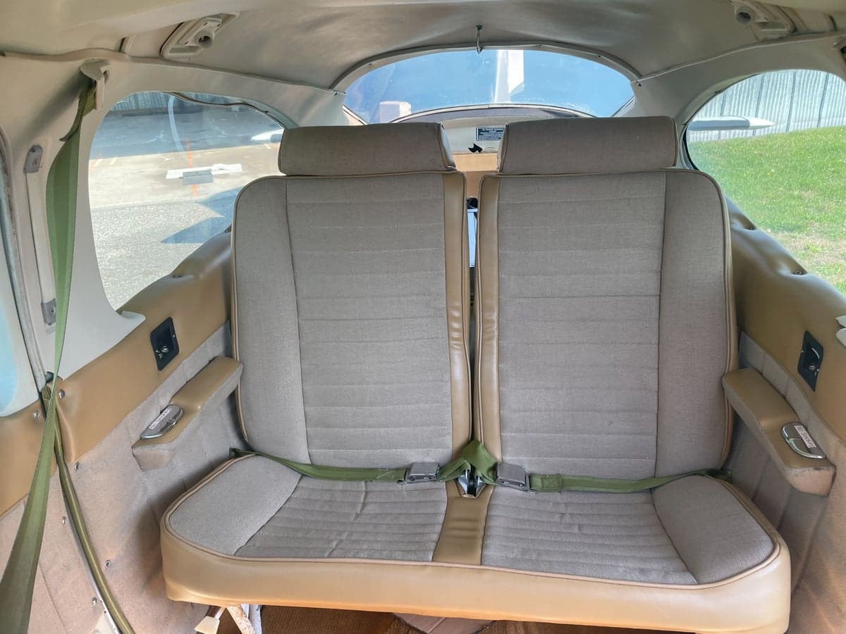 The rear seats of a Cessna Cardinal RG II, featuring tan upholstery and green seatbelts.