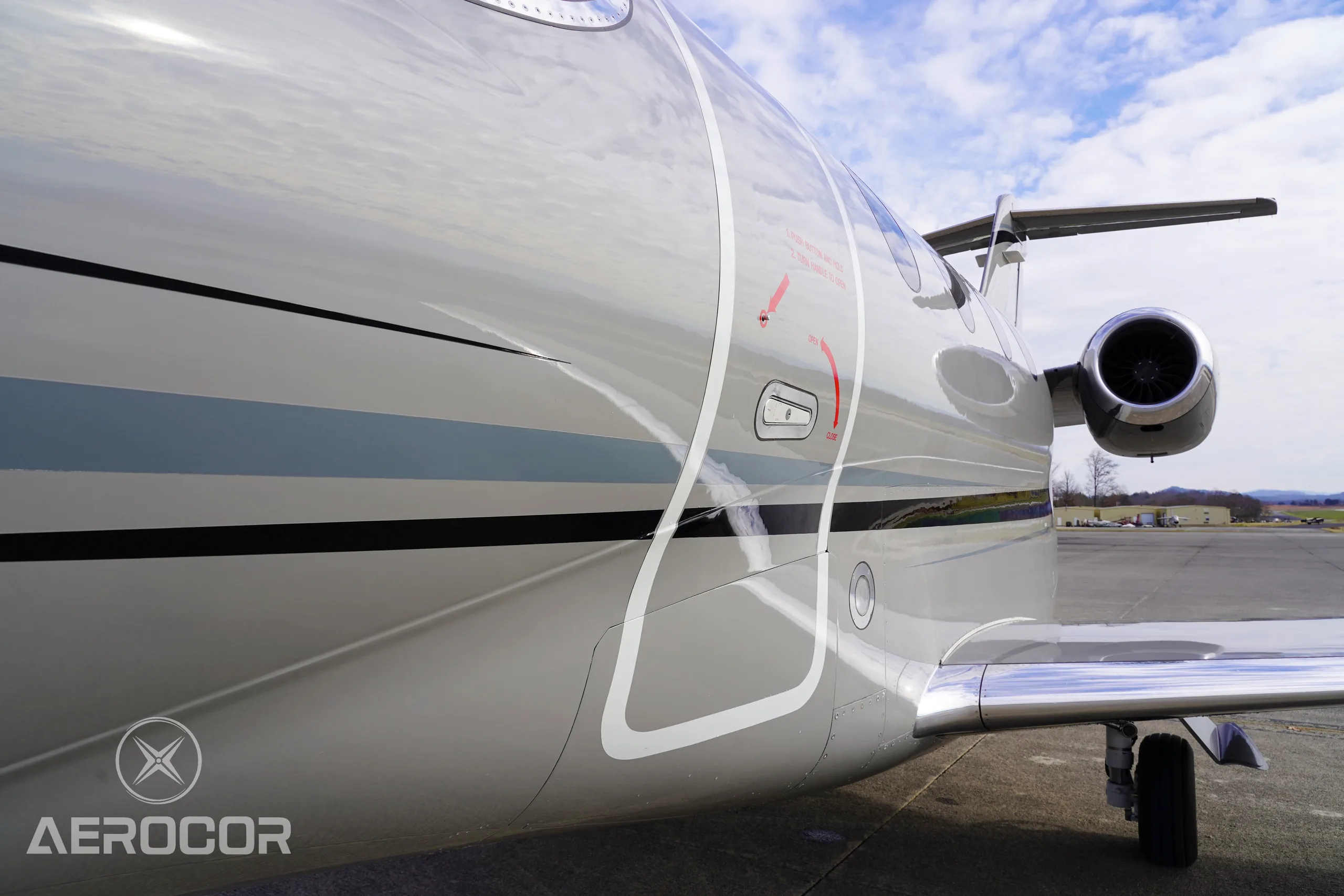 A close-up of the gray Raytheon Premier I fuselage showing the entry door outline and engine nacelle.
