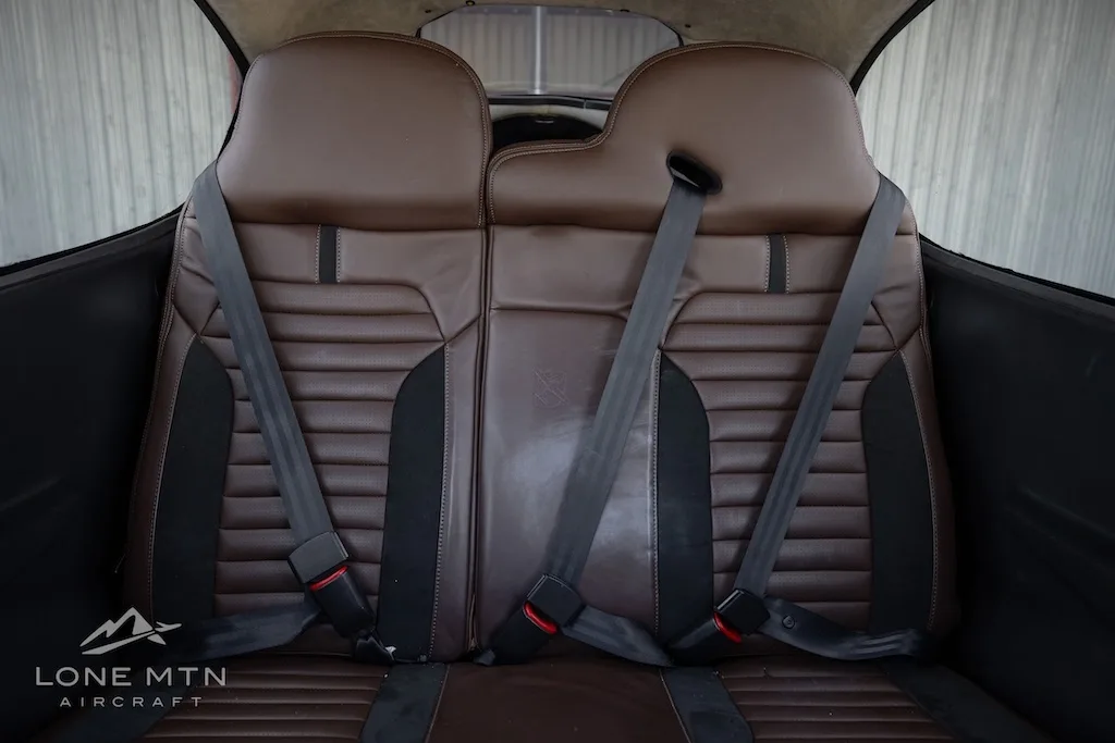 A close-up view of the brown leather rear passenger seats with seatbelts.