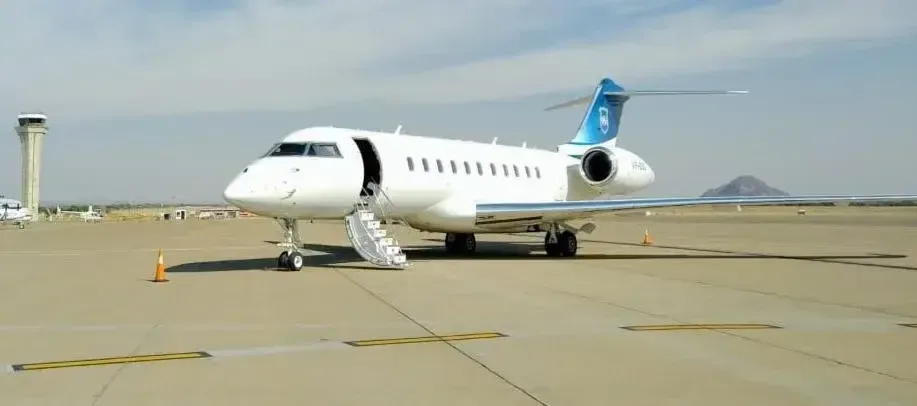 A white Bombardier Global Express business jet parked on the tarmac with the airstair deployed.