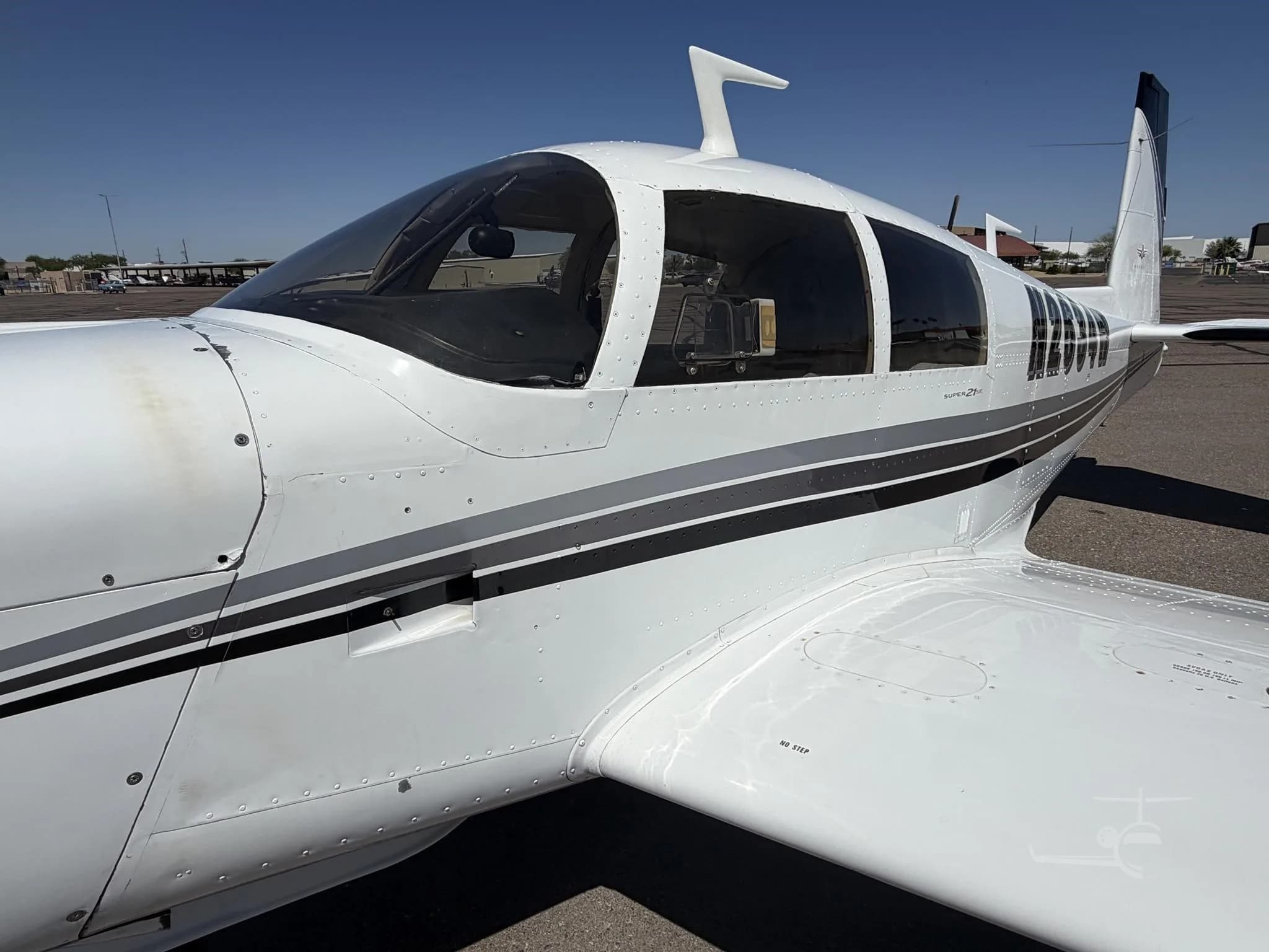 Side view of the Mooney M20J Super 21SE aircraft showing the cockpit windows and registration number.