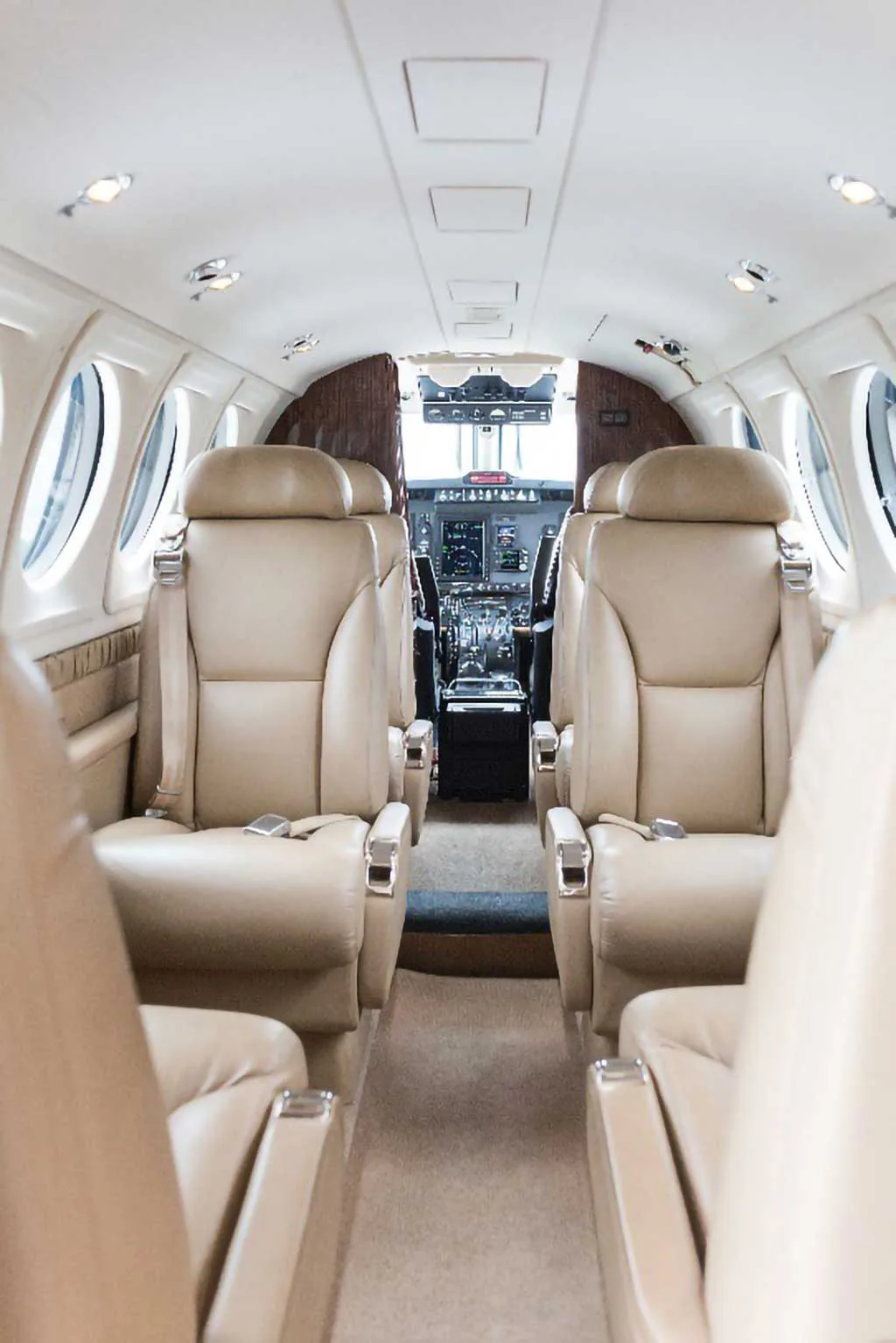 The interior cabin of a private aircraft features tan leather seats and a view into the cockpit.
