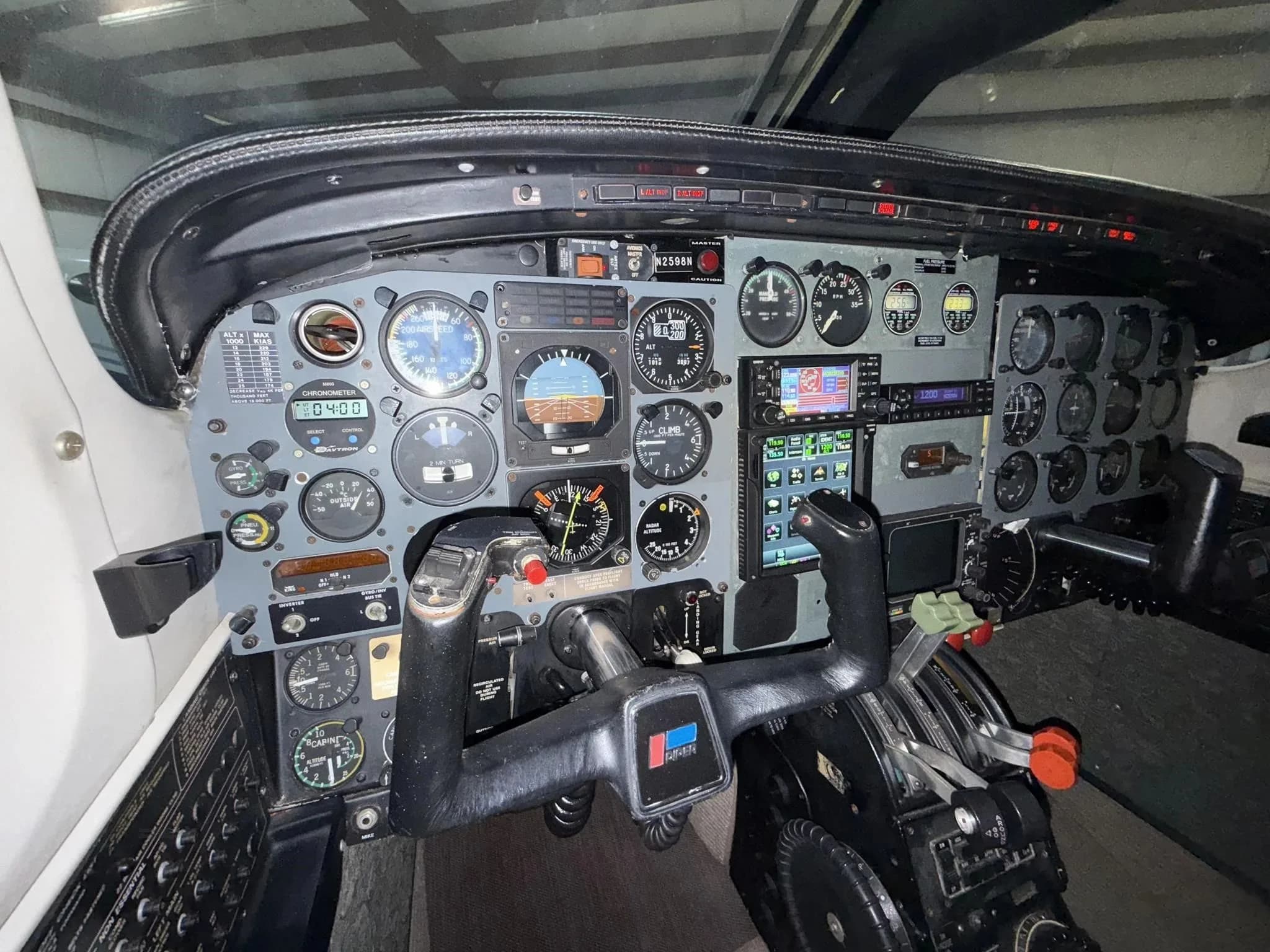 The cockpit of a Piper Navajo aircraft, showing the instrument panel with analog gauges and modern displays, and dual yokes.