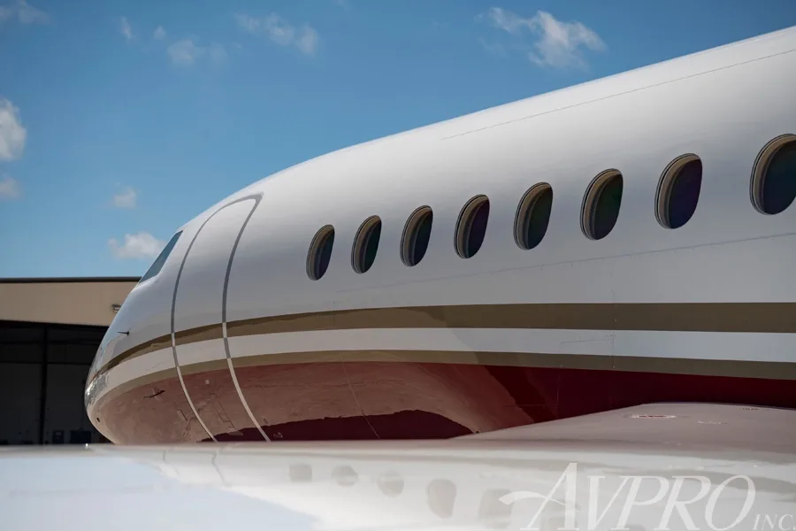 Close-up view of the white and red fuselage and passenger windows of the Dassault Falcon 900LX.